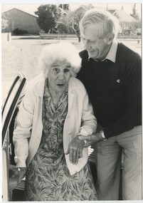 Elderly female assisted by male from car