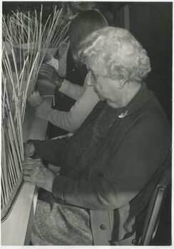 Group of people sit at a table making baskets