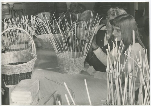 Group of people sit at a table making baskets