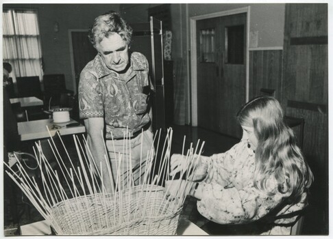 Man talks to girl who is making a basket