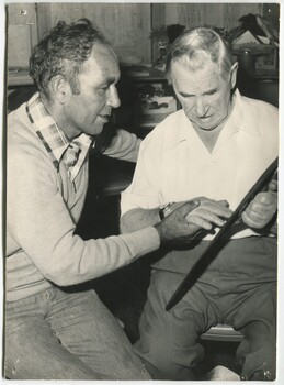Man helping another touch a weaving shuttlecock (?)