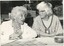 Two women chat whilst weaving looms sit in front of them