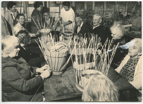 People sit around a table weaving baskets