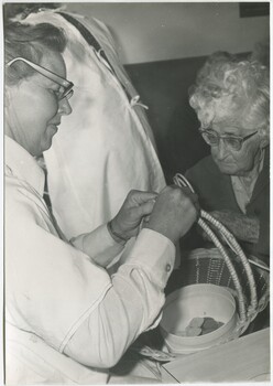Two women work on a basket