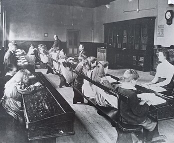 Students sit across two rows of desks in three separate classes in one room