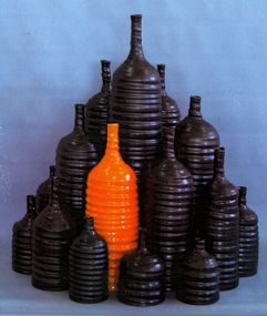 A number of back ceramic bottles, and one orange bottle.