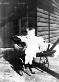 Photograph, One of the Palstra children in a cane pusher, 1921