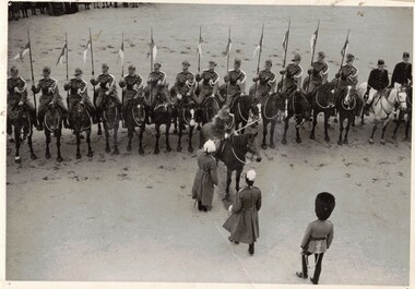 Men wearing bearskin hats inspecting line of soldiers on horses.