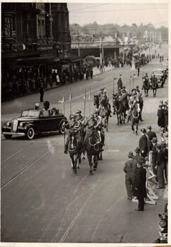 Soldiers with lances on horseback escorting car