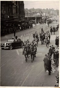 Soldiers with lances on horseback escorting car