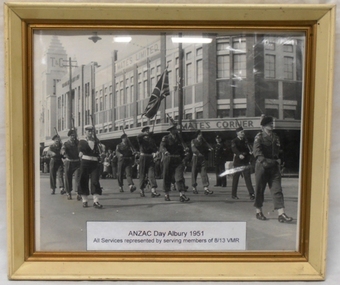 Servicemen marching with flag in city street