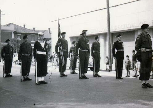 Servicemen formed up for a parade in city street.