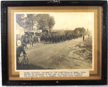 framed photograph of soldiers near horses and trucks