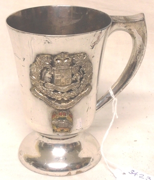 Silver mug with badges affixed to side.