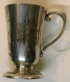 Silver cup with handle and inscription on side.