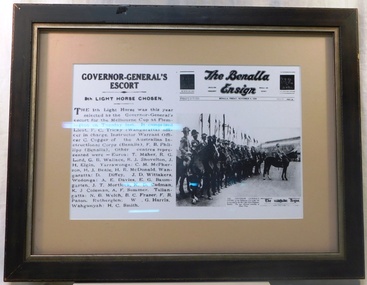 Framed newspaper cutting with photograph and text.