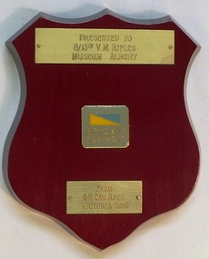 Small wooden shield with coloured badge and colour patch