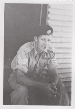Photograph of soldier sitting on hut step