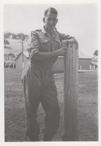 Photograph of soldier leaning on fence post