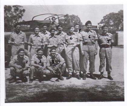 soldiers wearing berets in front of truck.