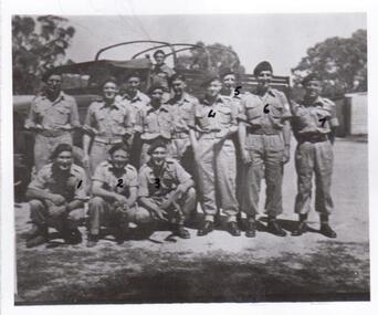 soldiers wearing berets in front of truck.