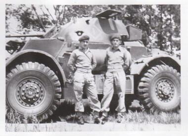 Two soldiers standing next to tank