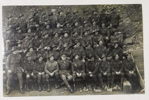 Postcard of large group of soldiers lined up in tiers. Letter on reverse of card.