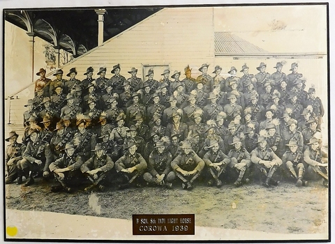 Large group of soldiers posed in front of building.
