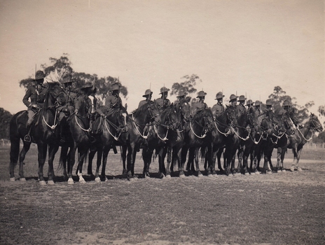 Line of fifteen soldiers with swords on horses.