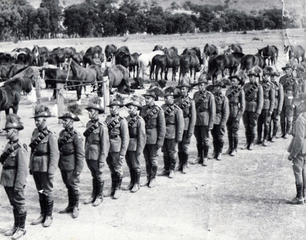 Soldiers parading in front of horses.