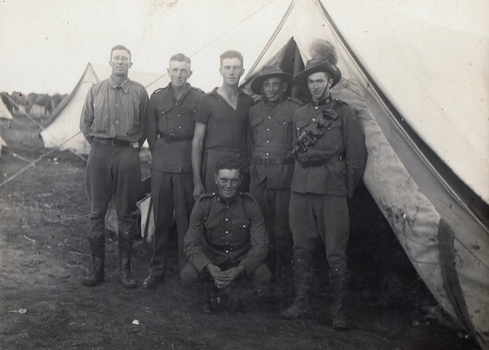 Six soldiers outside a tent.
