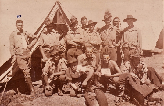 A group of soldiers in working clothes outside a tent.