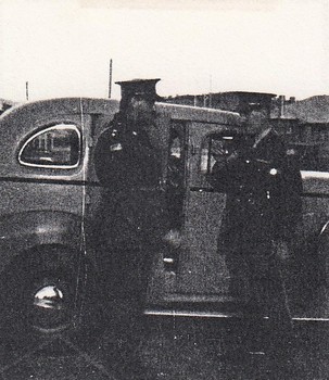 Two soldiers wearing caps near car
