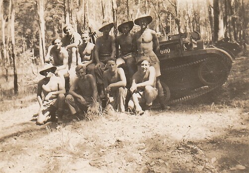 Soldiers without shirts near tracked vehicle