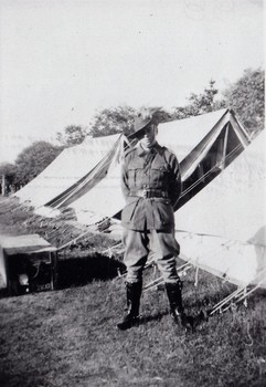 Soldier standing beside row of tents.