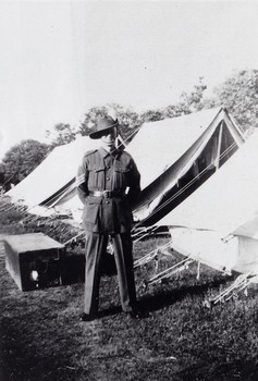 A sergeant standing beside row of tents.