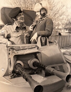 Soldier in army vehicle with young boy wearing headphones