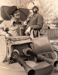 Soldier in army vehicle with young boy wearing headphones