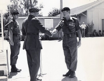 Three soldiers, two are shaking hands