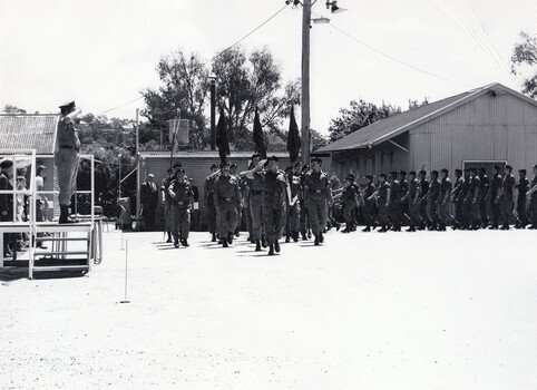 Soldiers marching, officer on dias saluting.