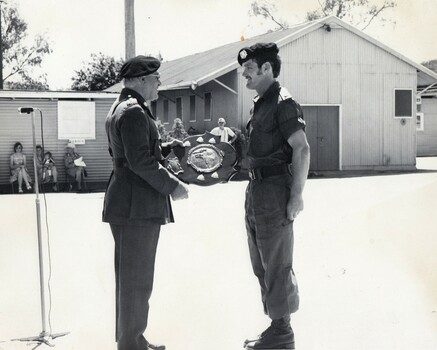 Army officer presenting a trophy to a solbier