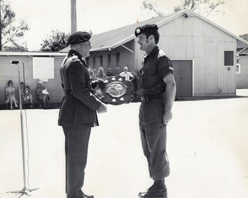 Army officer presenting a trophy to a solbier