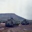 Two tracked vehicles in muddy ground.