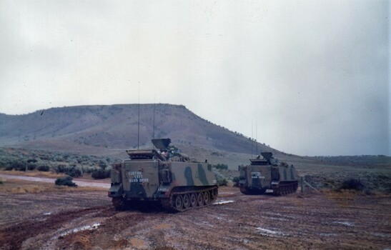 Two tracked vehicles in muddy ground.