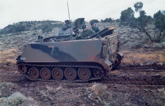Tracked army vehicle with hills in background.