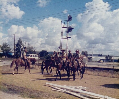 Soldiers on horses near railway warning lights 