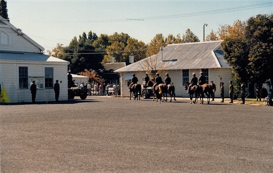 six light horsemen with swords on a parade ground.