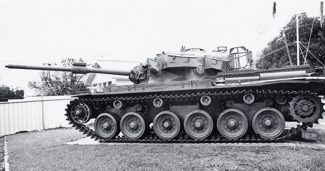 Large tank in a fenced lawn in front of flag pole