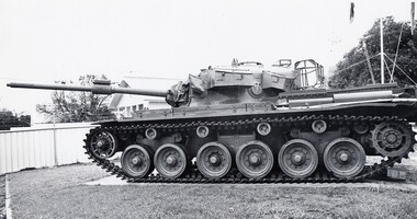 Large tank in a fenced lawn in front of flag pole