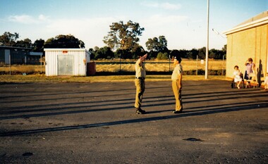 Two soldiers on a parade ground saluting 